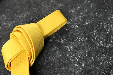 Photo of Yellow karate belt on gray textured background, space for text