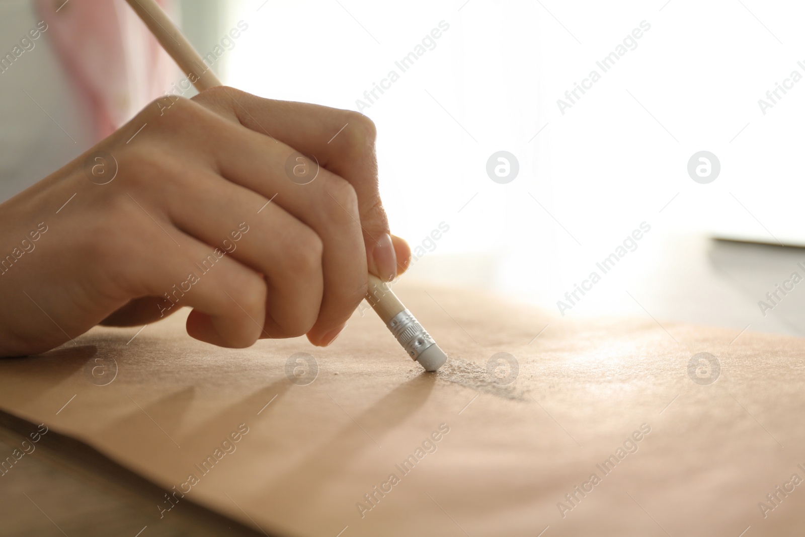 Photo of Woman correcting picture on paper with pencil eraser, closeup