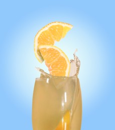 Image of Splashing freshly made lemon juice on light blue background. Slices of citrus fruit falling into glass