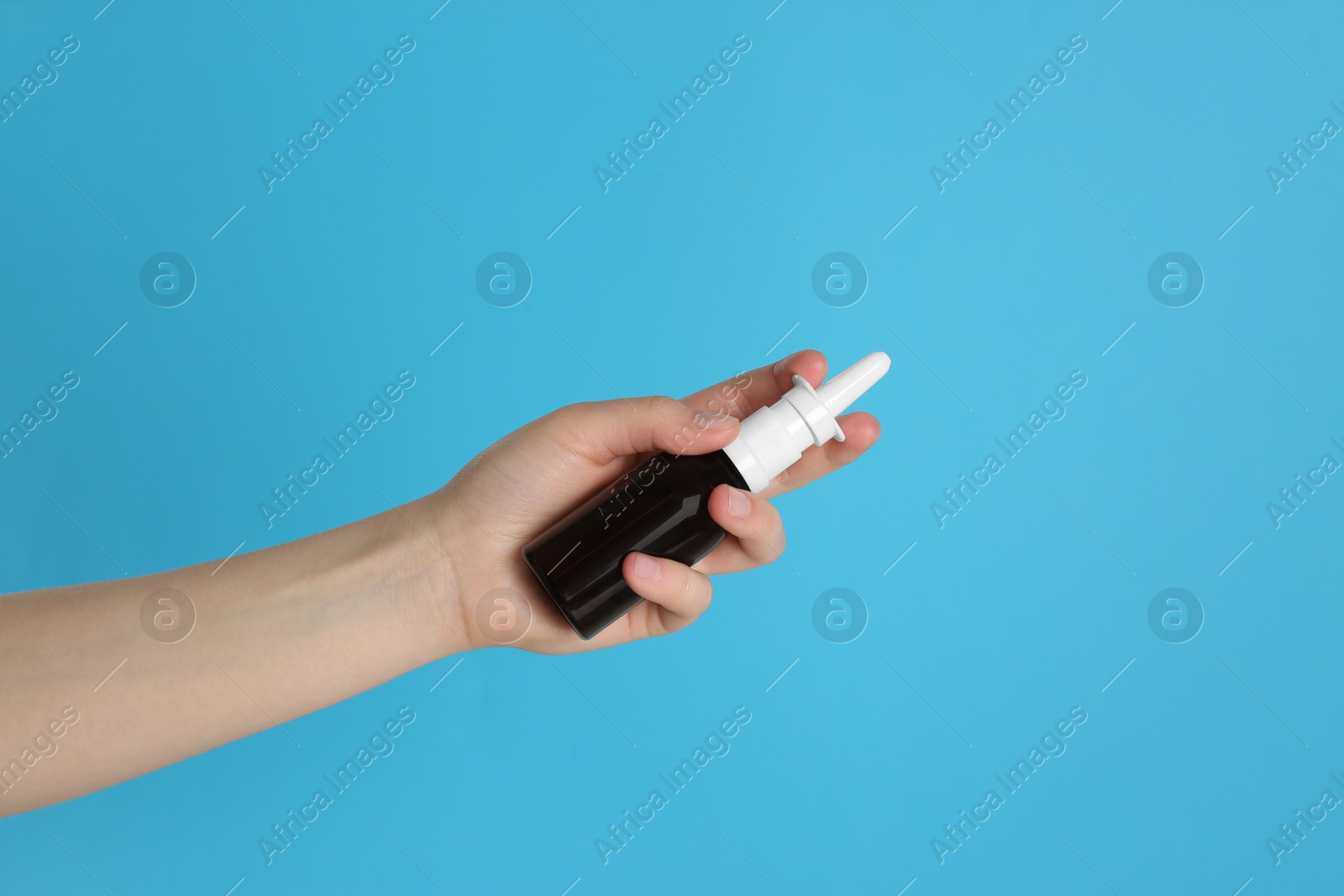 Photo of Woman holding nasal spray on light blue background, closeup