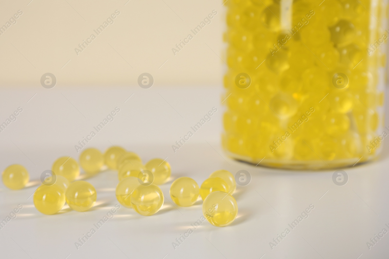Photo of Yellow filler and glass vase on white table, closeup. Water beads