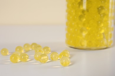 Yellow filler and glass vase on white table, closeup. Water beads