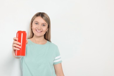 Photo of Beautiful happy woman holding red beverage can on light background. Space for text