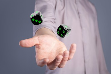 Image of Man throwing black dice on grey background, closeup