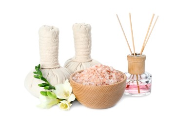 Photo of Spa composition. Herbal massage bags, sea salt, reed air freshener and beautiful flowers on white background