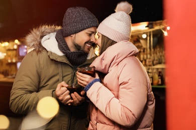 Happy couple with mulled wine at winter fair