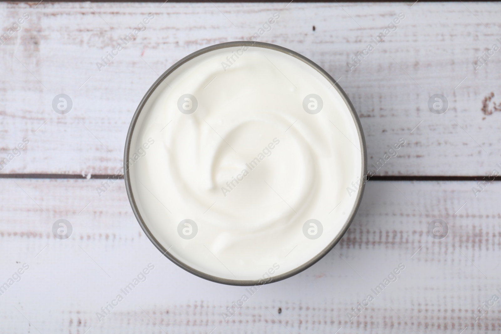 Photo of Delicious natural yogurt in bowl on light wooden table, top view