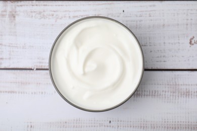 Delicious natural yogurt in bowl on light wooden table, top view