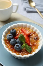 Delicious creme brulee with berries and mint in bowl on table, closeup
