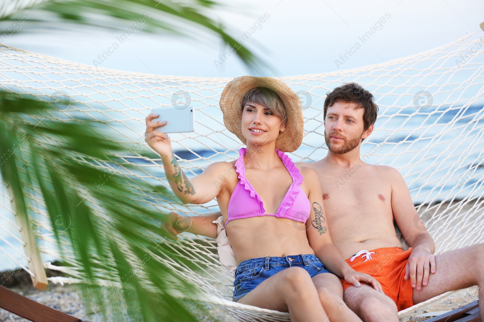 Photo of Young couple taking selfie in hammock on beach