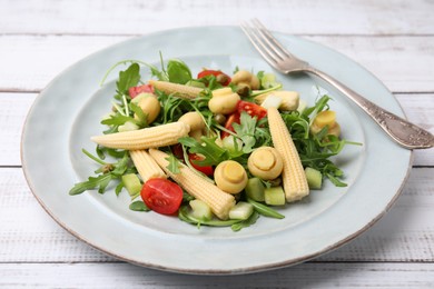 Photo of Tasty baby corn with vegetables, arugula and mushrooms on white wooden table, closeup