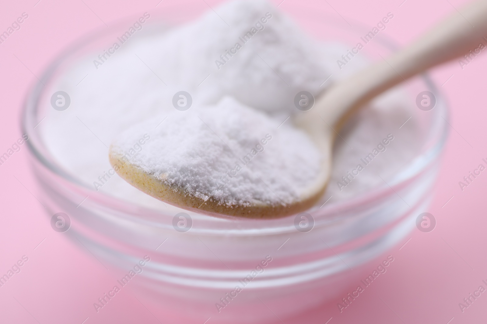 Photo of Bowl and spoon of sweet powdered fructose on pink background, closeup