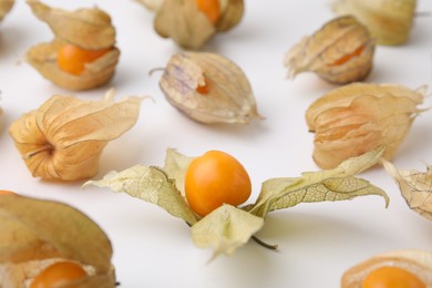 Photo of Ripe physalis fruits with calyxes on white background, closeup