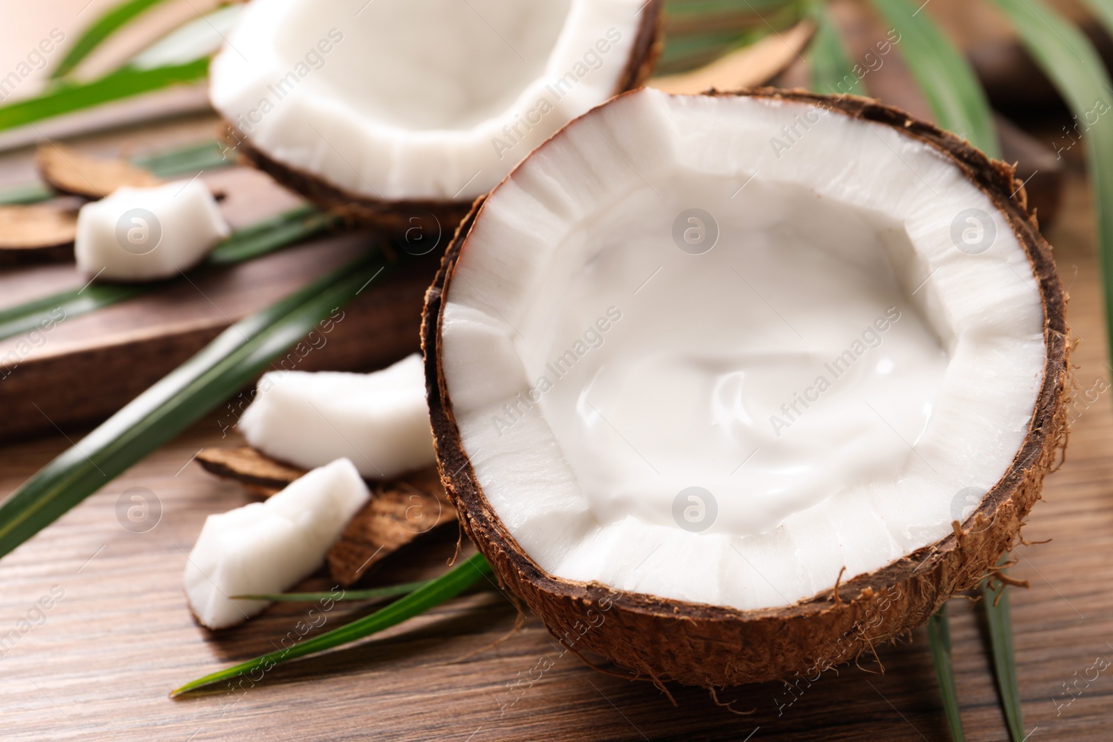 Photo of Ripe coconut with cream on wooden table. Space for text