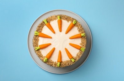 Dish with tasty carrot cake on blue background, top view