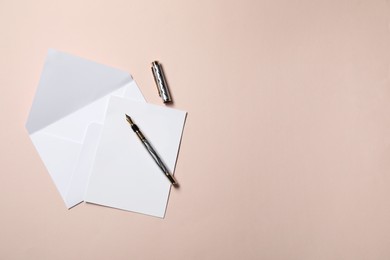 Photo of Blank sheet of paper, letter envelope and pen on beige background, top view. Space for text