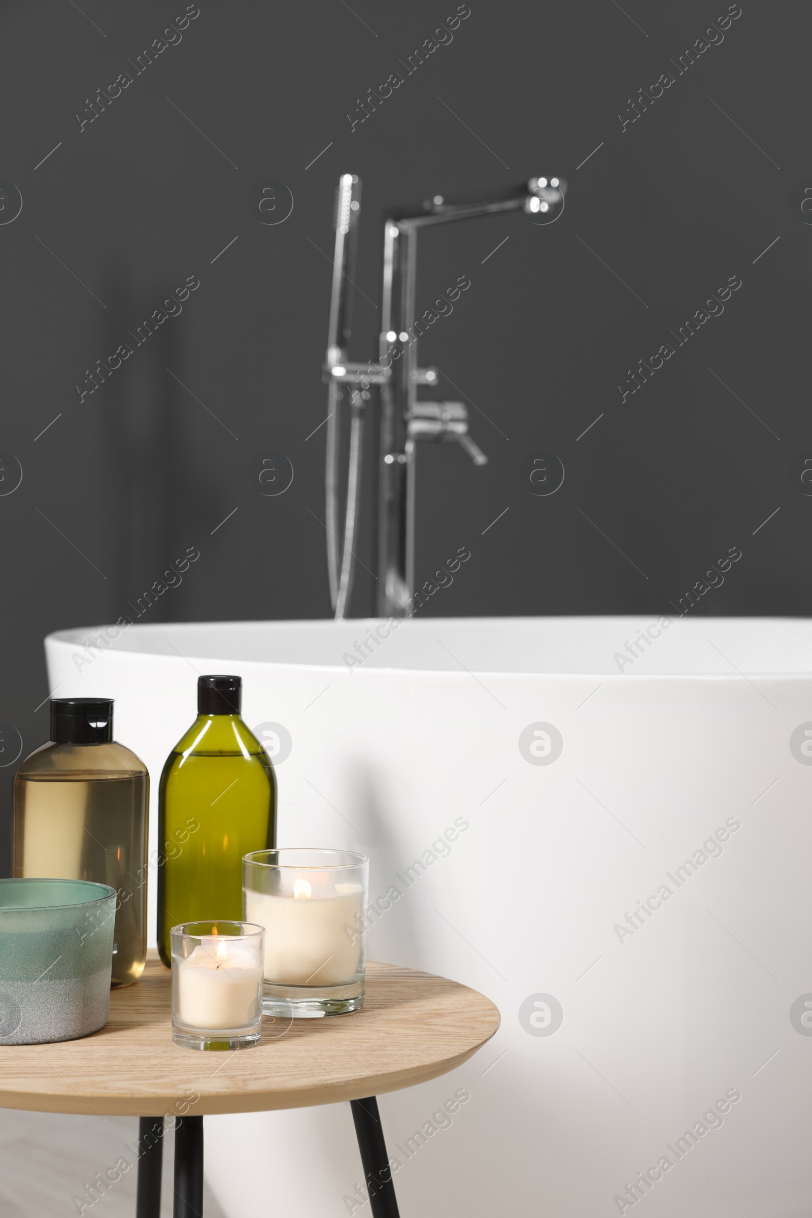 Photo of Candles and care products on table in bathroom. Space for text