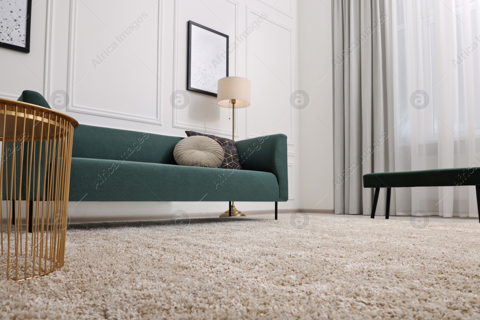 Photo of Stylish living room with soft beige carpet, coffee table and sofa, low angle view. Interior design