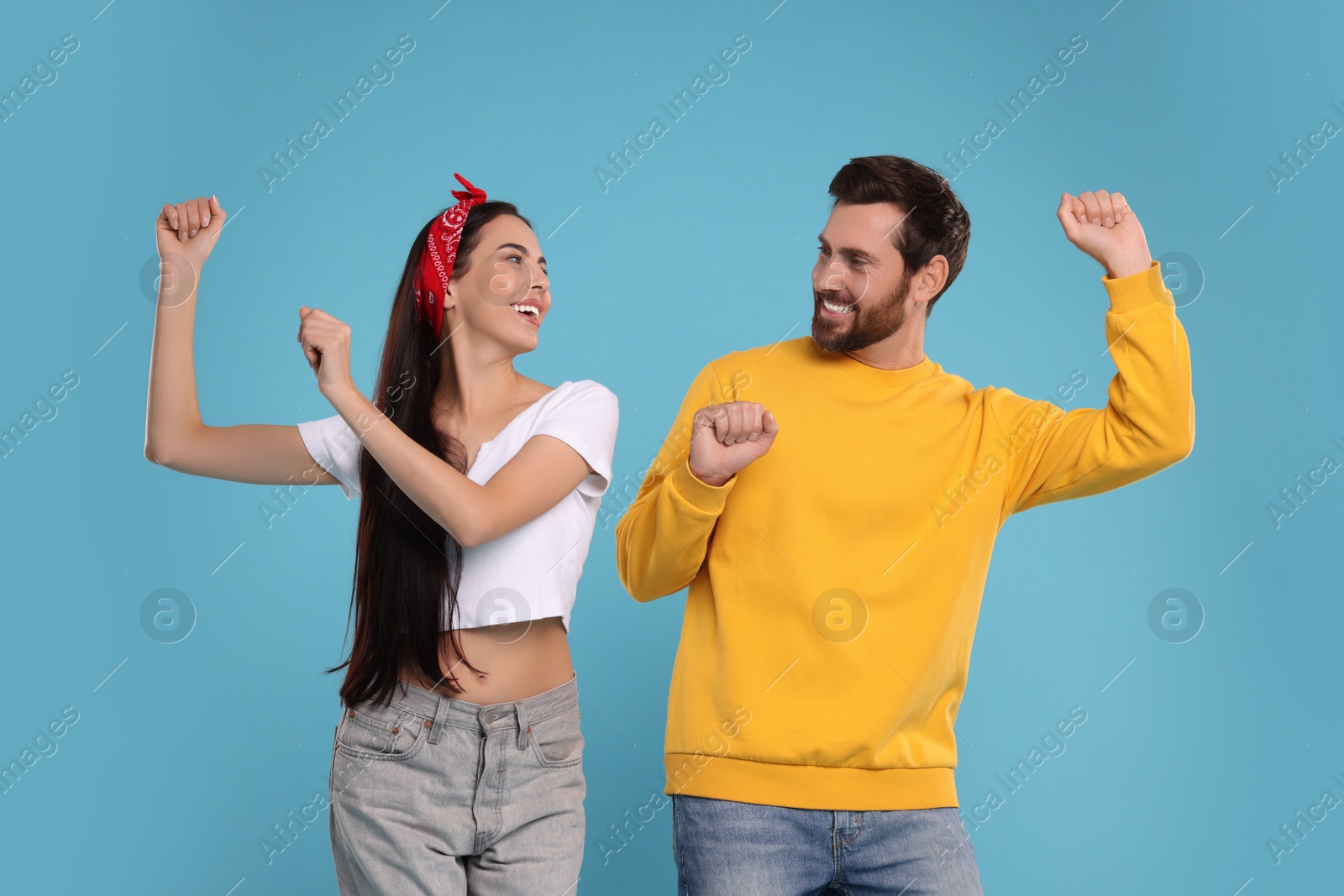 Photo of Happy couple dancing together on light blue background