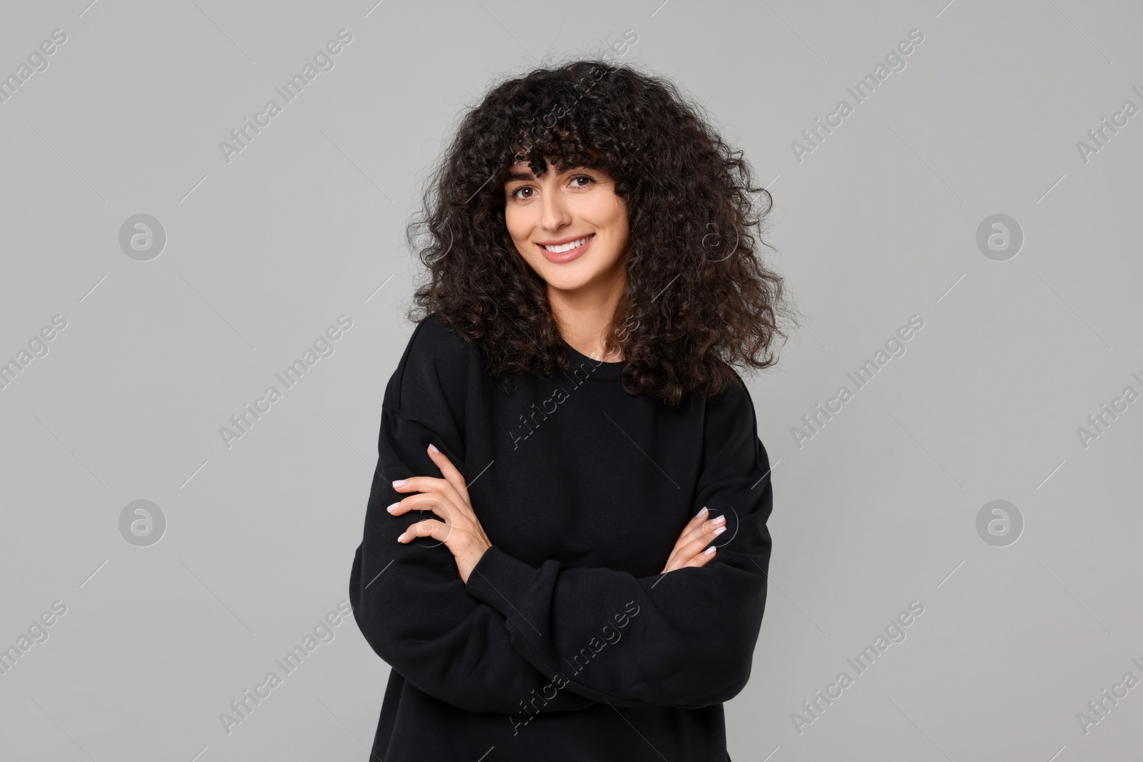 Photo of Happy young woman in stylish black sweater on light grey background