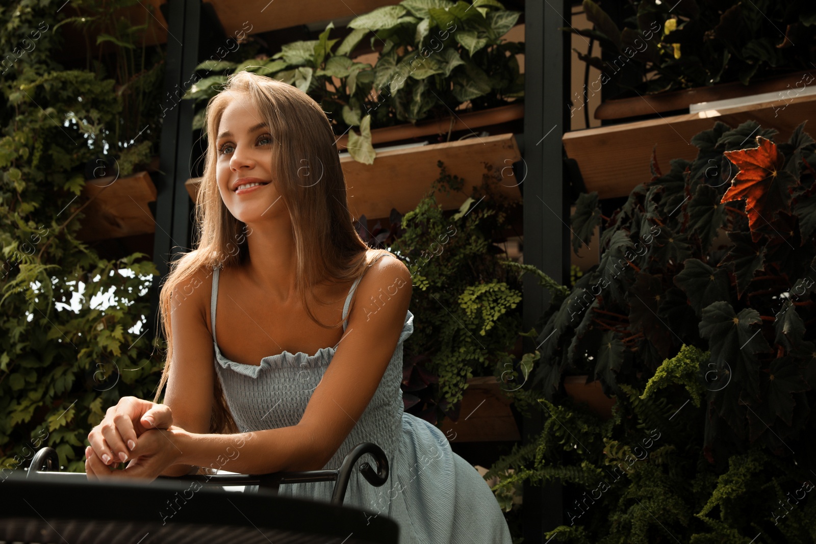 Photo of Beautiful young woman standing on balcony, space for text