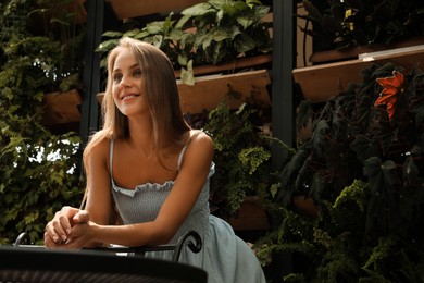 Photo of Beautiful young woman standing on balcony, space for text