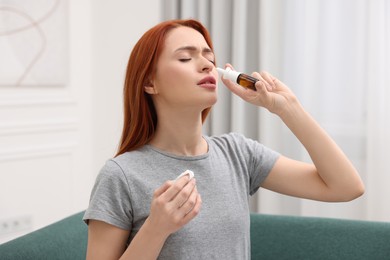 Photo of Medical drops. Woman with tissue using nasal spray at home