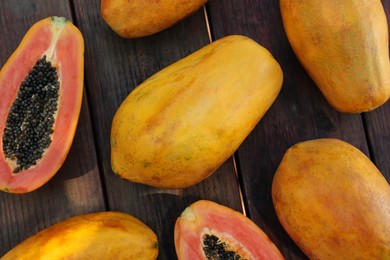 Fresh ripe cut and whole papaya fruits on wooden table, flat lay