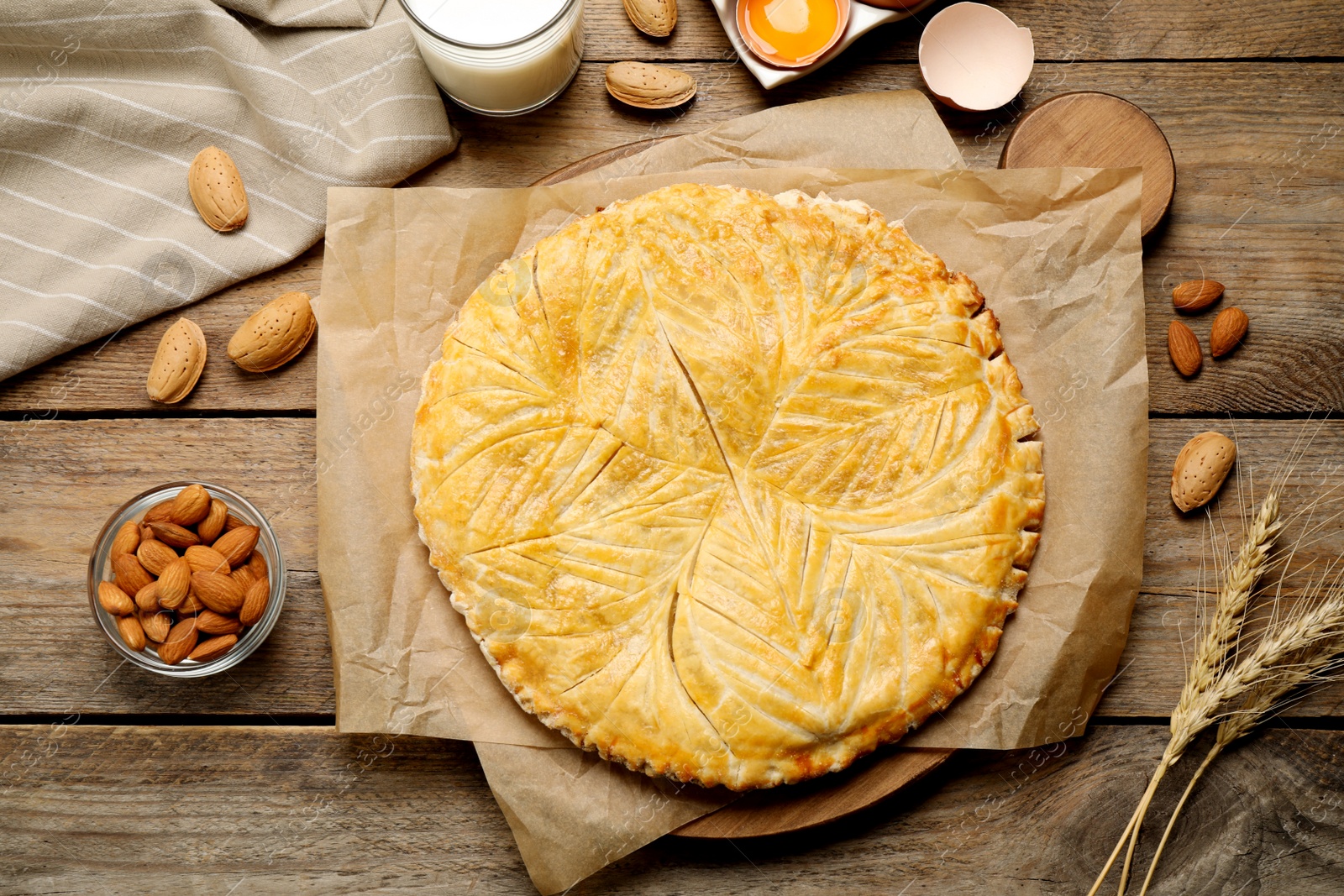 Photo of Traditional galette des rois and ingredients on wooden table, flat lay