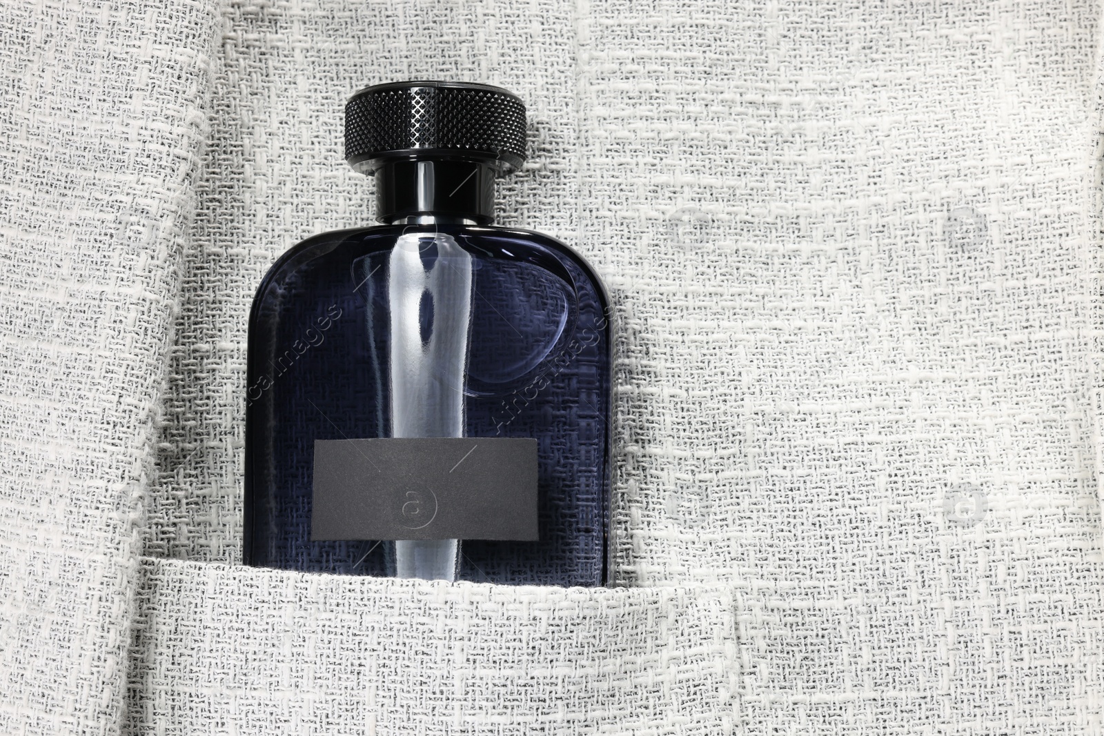 Photo of Luxury men's perfume in pocket of grey jacket, top view. Space for text