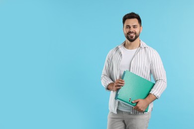 Photo of Happy man with folder on light blue background, space for text