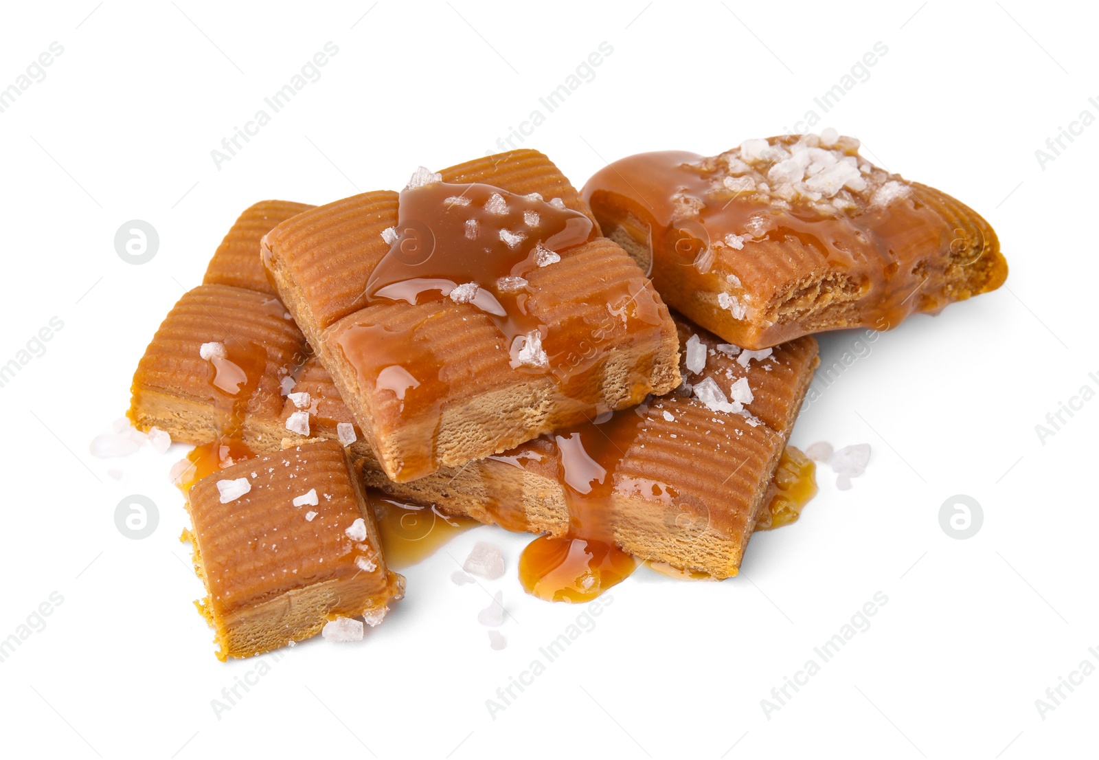 Photo of Yummy caramel candies and sea salt isolated on white