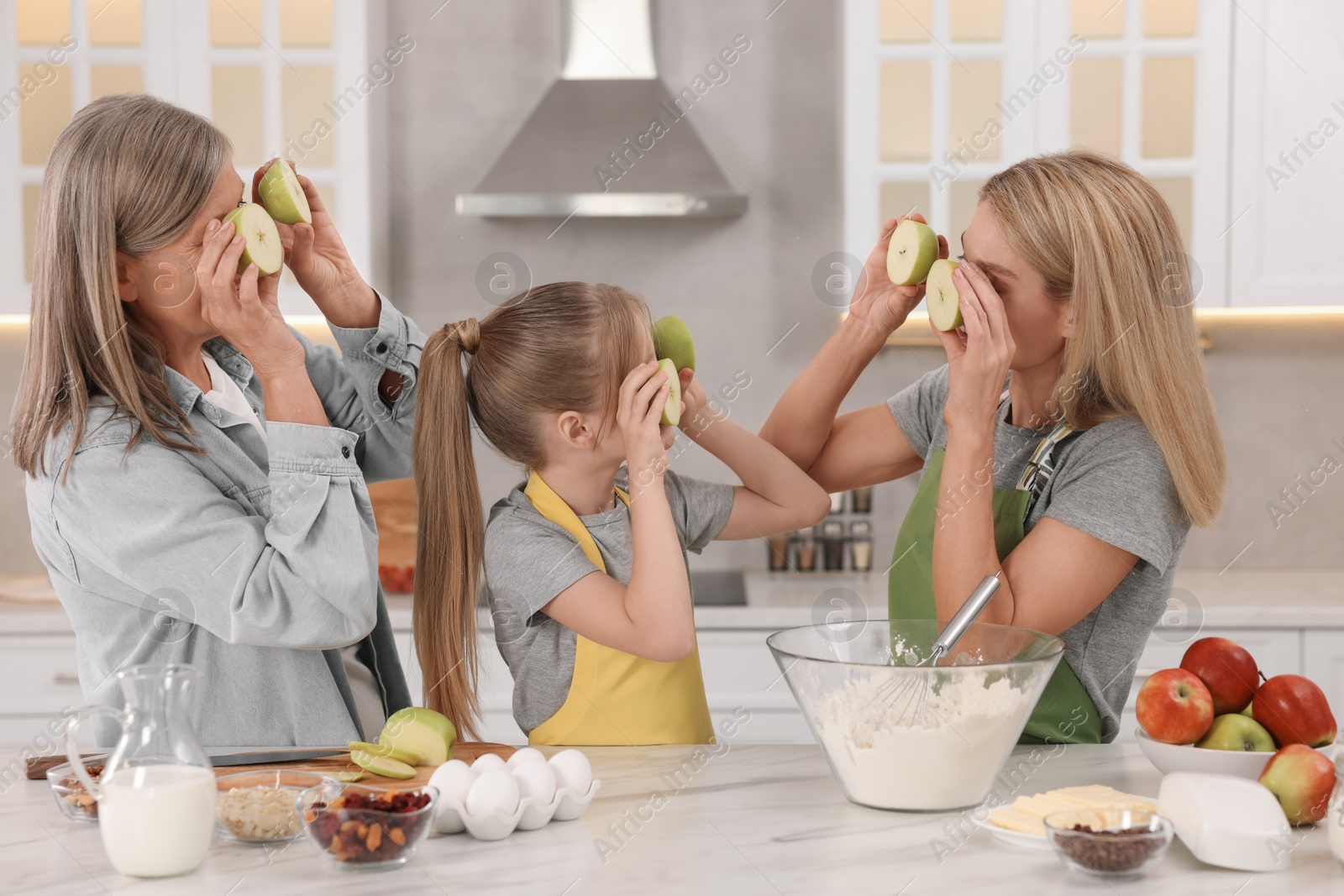 Photo of Three generations. Happy grandmother, her daughter and granddaughter having fun while cooking together in kitchen