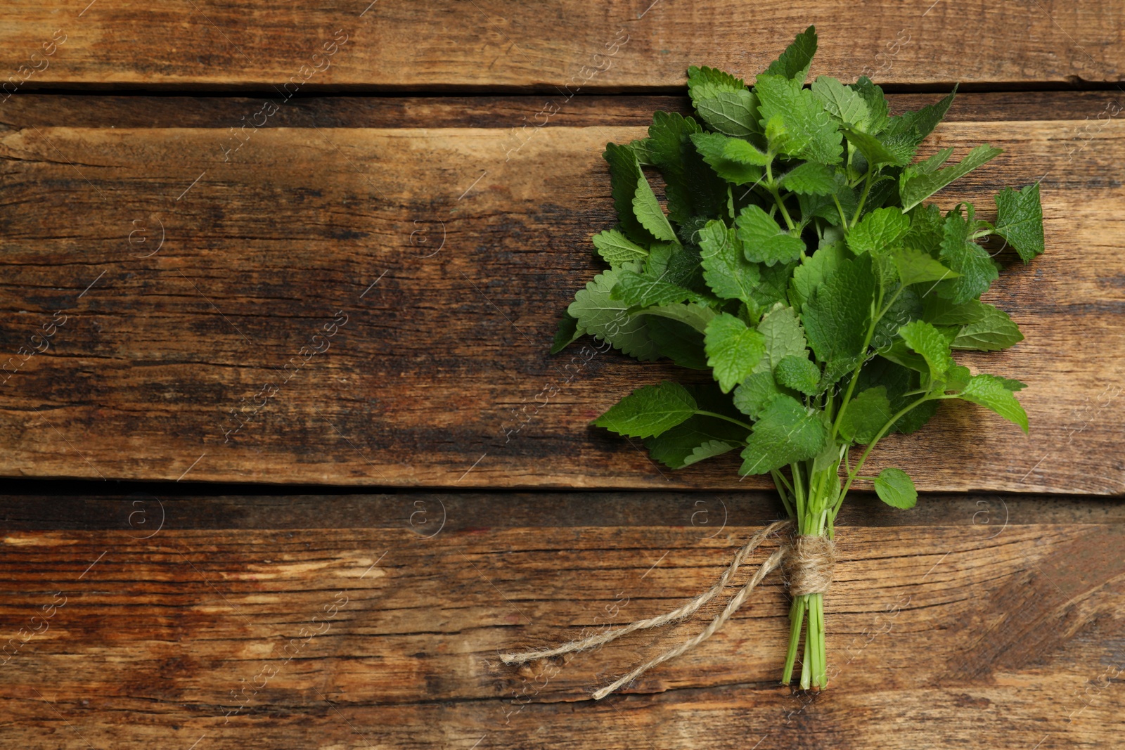 Photo of Bunch of fresh green lemon balm on wooden table, top view. Space for text