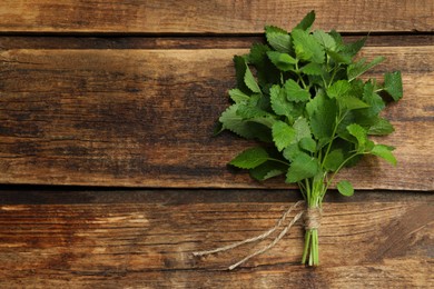 Photo of Bunch of fresh green lemon balm on wooden table, top view. Space for text