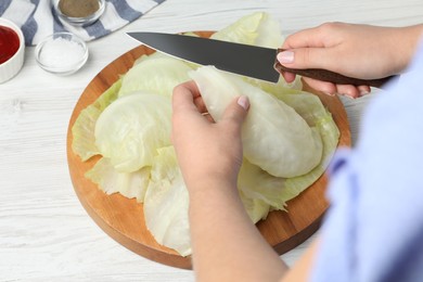 Woman preparing stuffed cabbage rolls at white wooden table, closeup