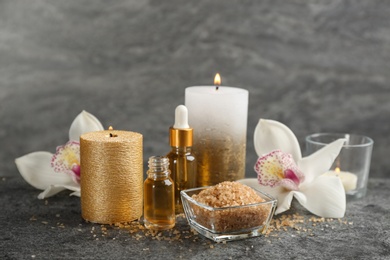 Photo of Beautiful spa composition with essential oil, candles and flowers on grey table