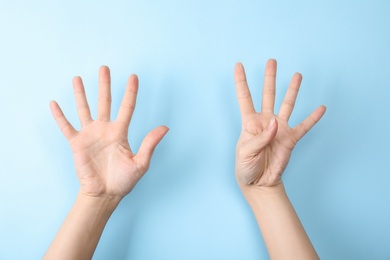 Woman showing sign nine on color background, closeup. Body language