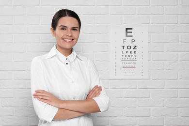 Photo of Ophthalmologist near vision test chart on white brick wall