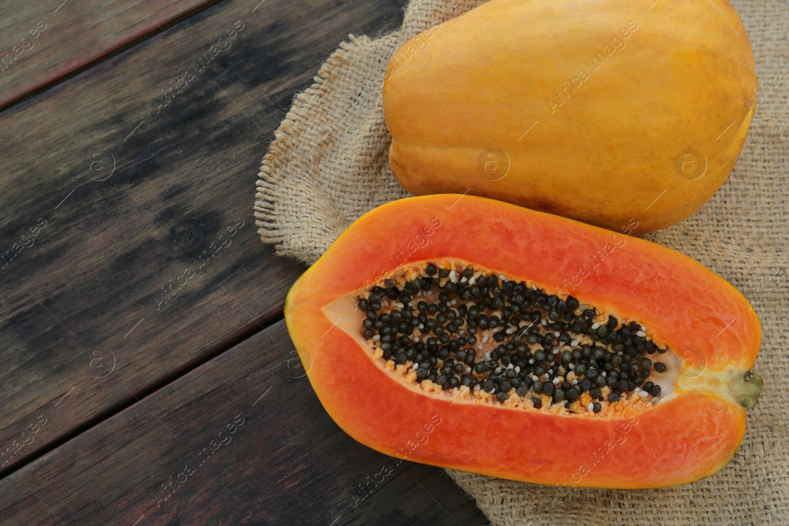 Photo of Tasty cut and whole papaya fruits on wooden table, top view. Space for text