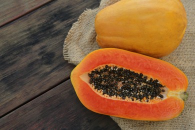 Photo of Tasty cut and whole papaya fruits on wooden table, top view. Space for text