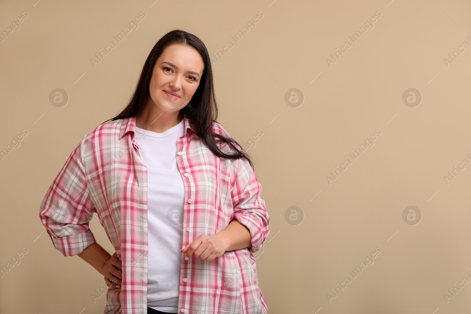 Photo of Beautiful overweight woman with charming smile on beige background. Space for text