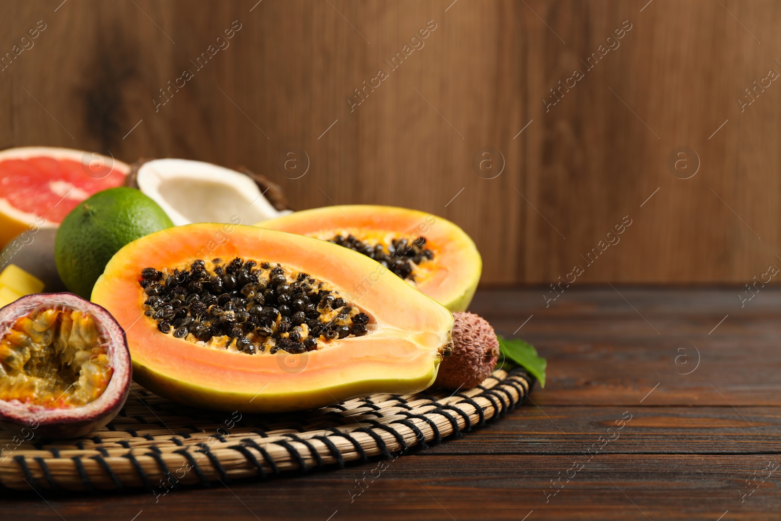 Photo of Fresh ripe papaya and other fruits on wooden table. Space for text