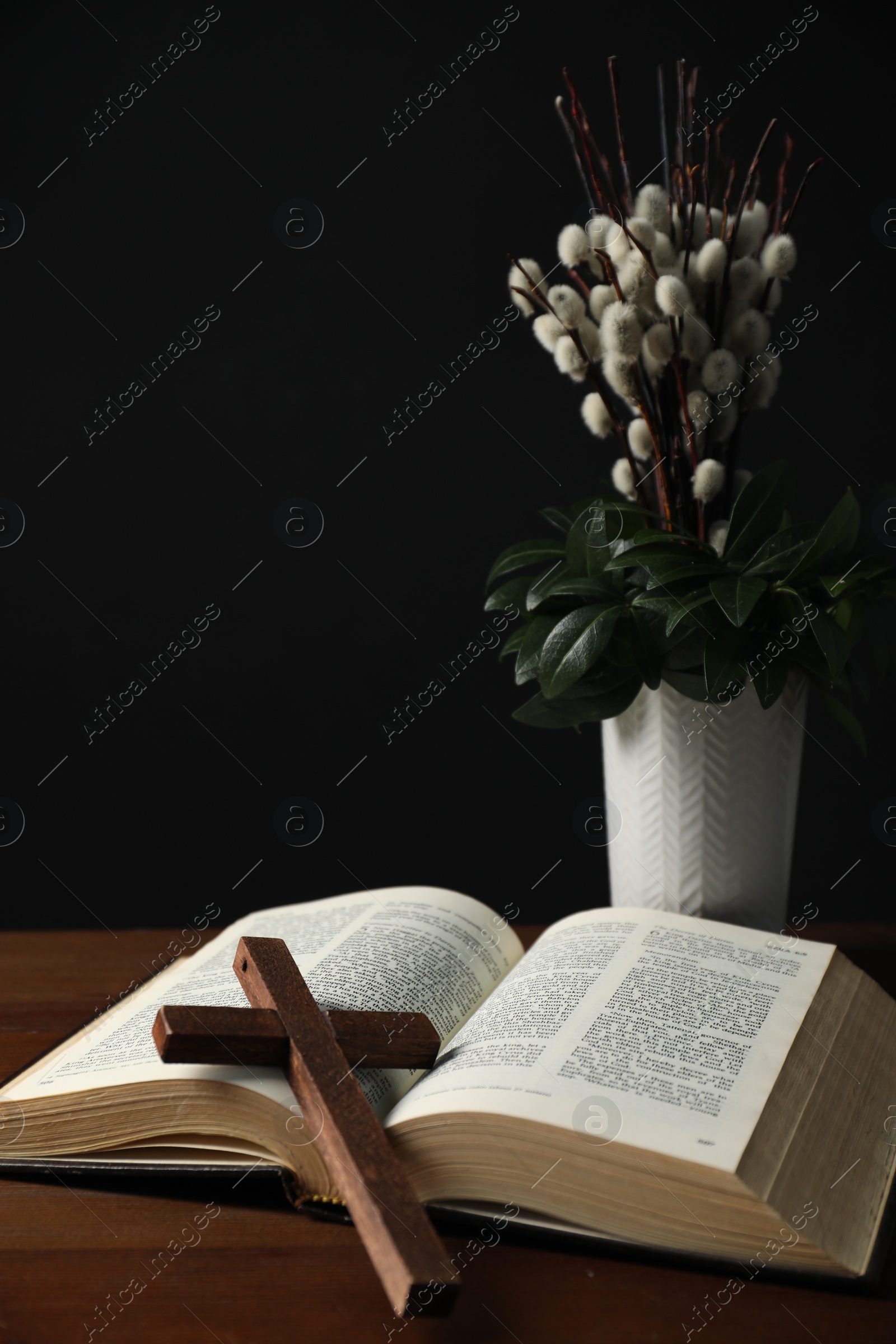 Photo of Bible, plant with willow branches and cross on wooden table