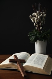 Photo of Bible, plant with willow branches and cross on wooden table