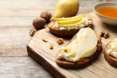 Photo of Toasted bread with tasty cream cheese and pear on wooden table. Space for text