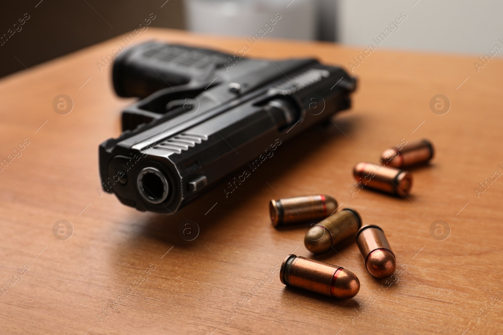 Photo of Semi-automatic pistol and bullets on wooden table indoors, closeup