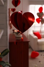 Photo of Cozy living room decorated for Valentine's Day, focus on red foil heart