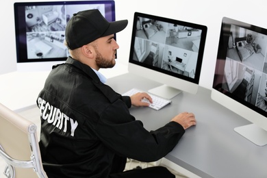 Photo of Male security guard monitoring home cameras indoors