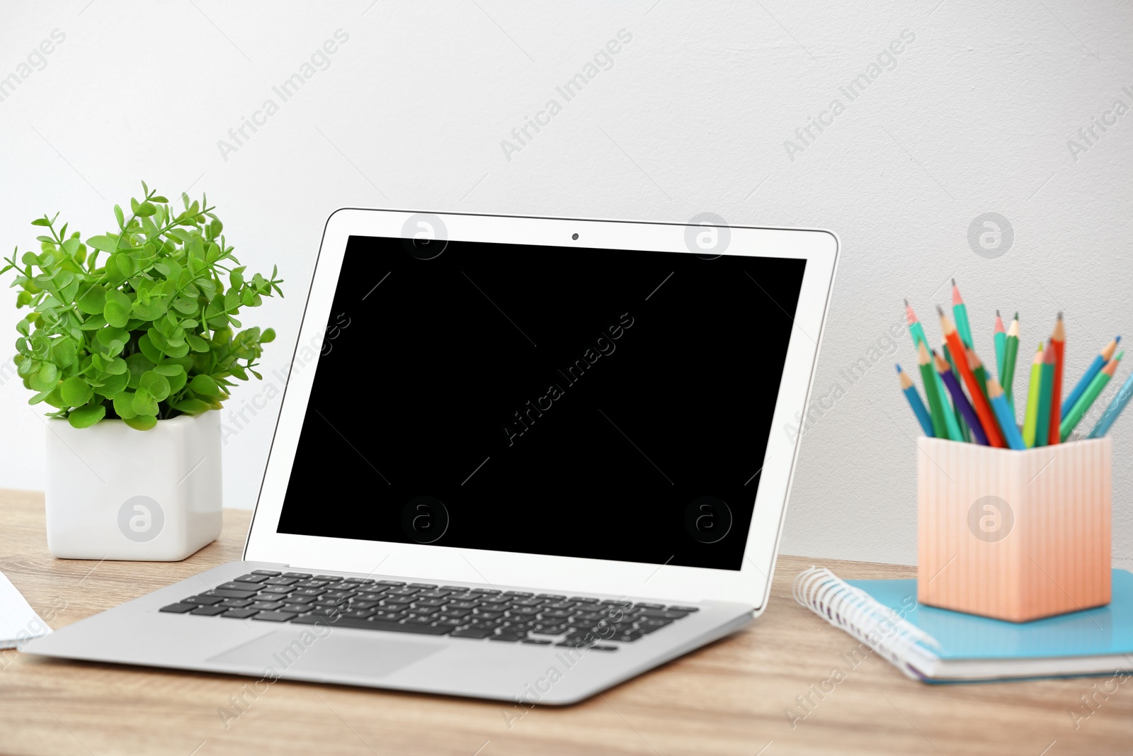 Photo of Modern laptop on table against light wall. Mock up with space for text